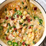 top view of salmon chowder in a Dutch oven with potatoes, corn and bacon
