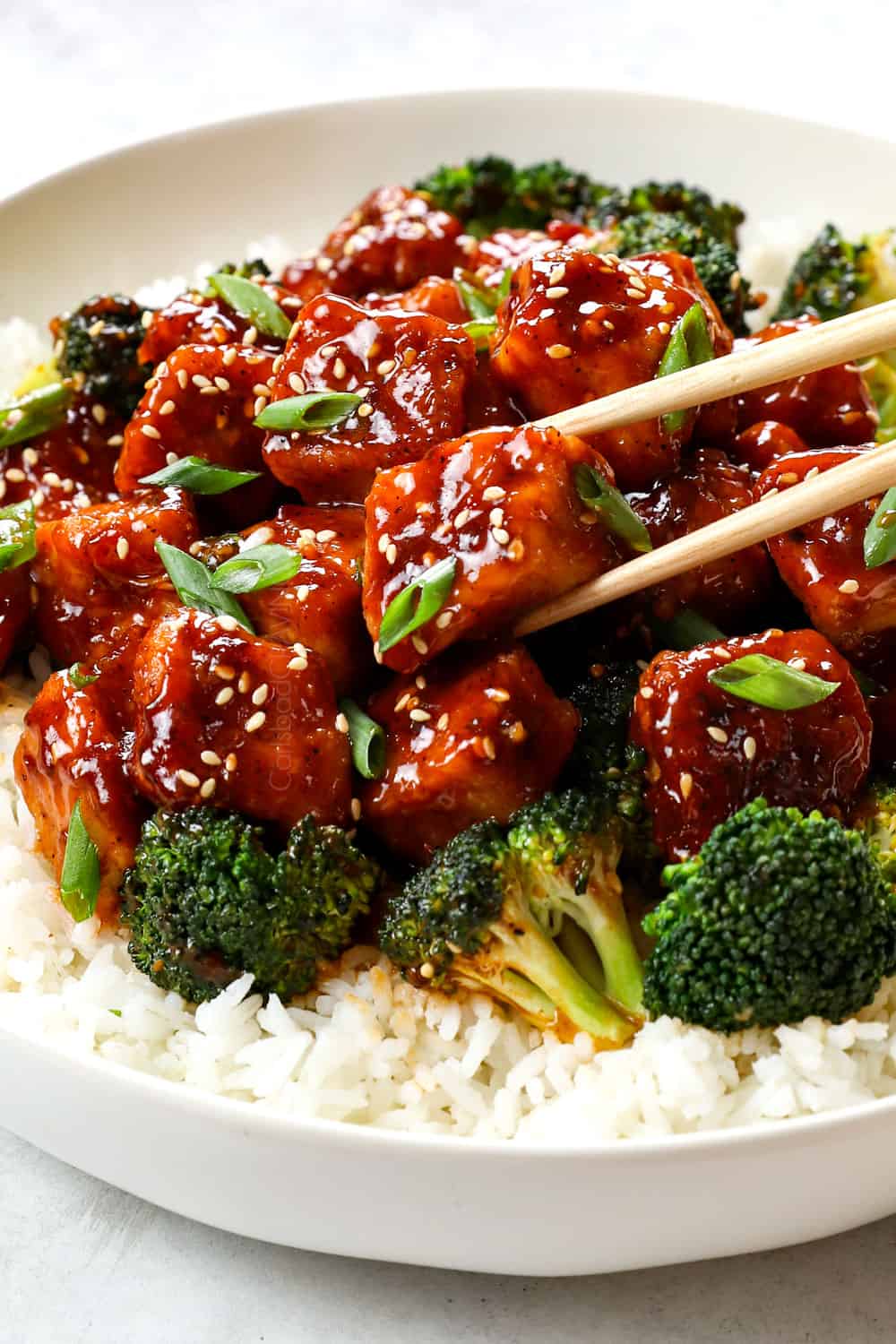 up close of picking up sesame chicken with chopsticks