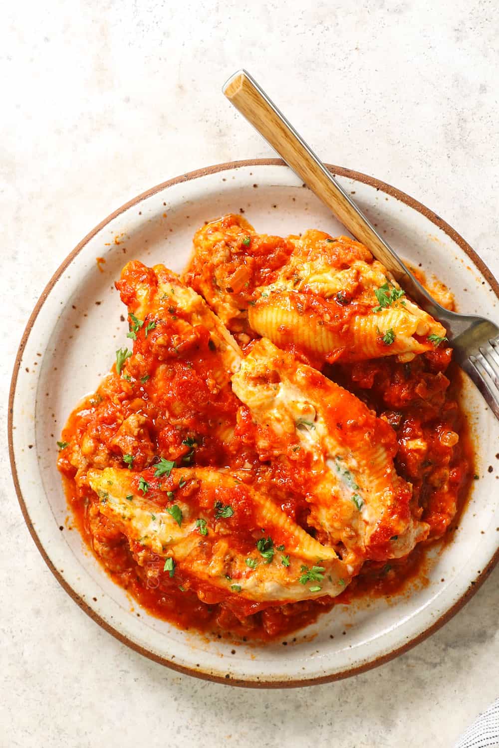 top view of a plate of stuffed shells with meat showing how saucy they are