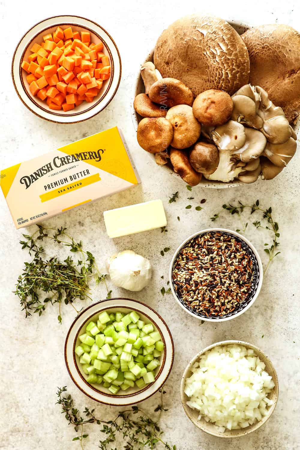 top view of showing how to make mushroom soup recipe with ingredients laid out: mushrooms, butter, wild rice, carrots, celery, thyme and garlic