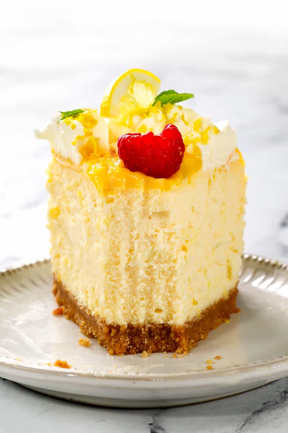 up close of a piece lemon cheesecake with a bite taken out showing how creamy it is