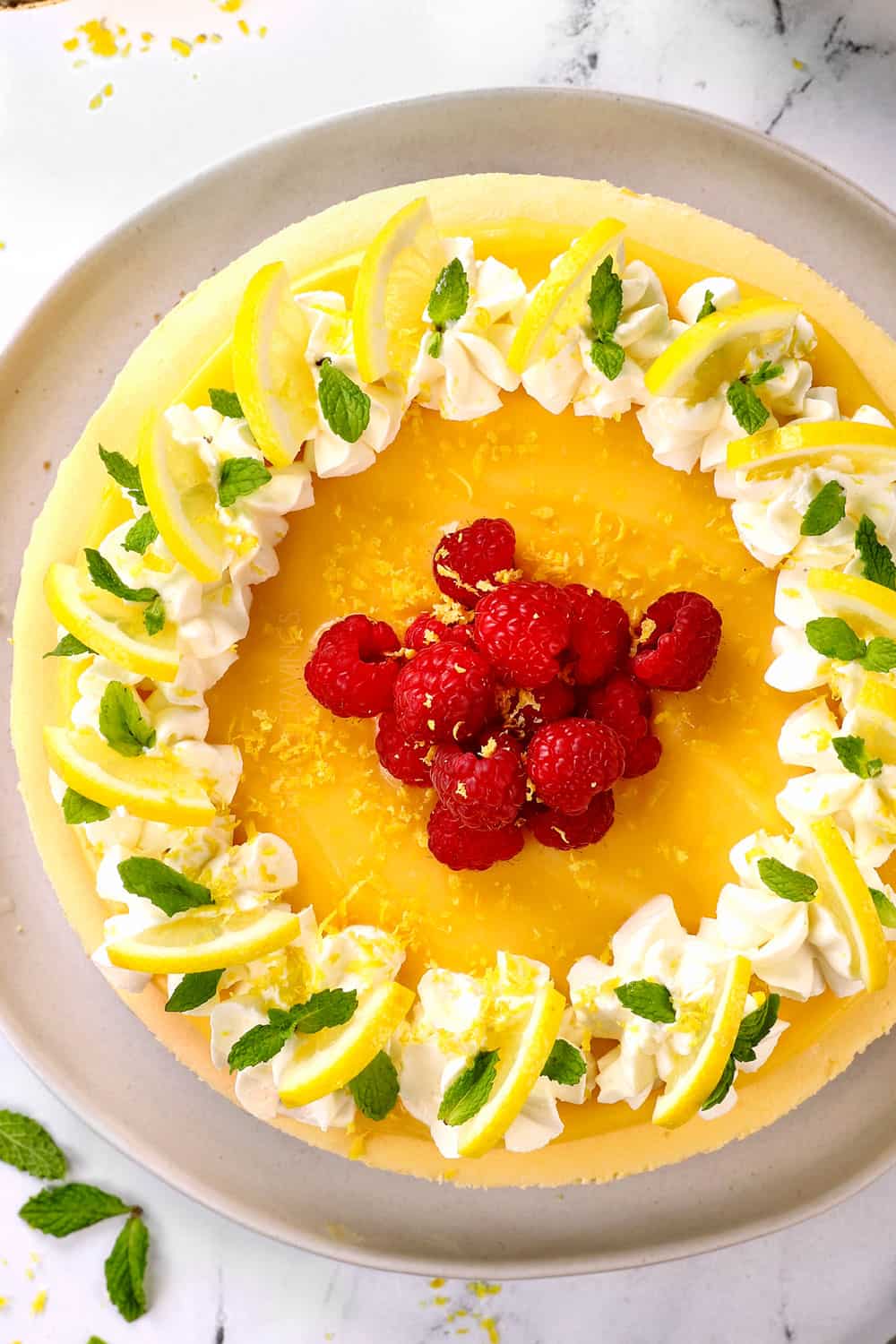 top view of lemon cheesecake recipe with lemon curd, raspberries and whipped cream