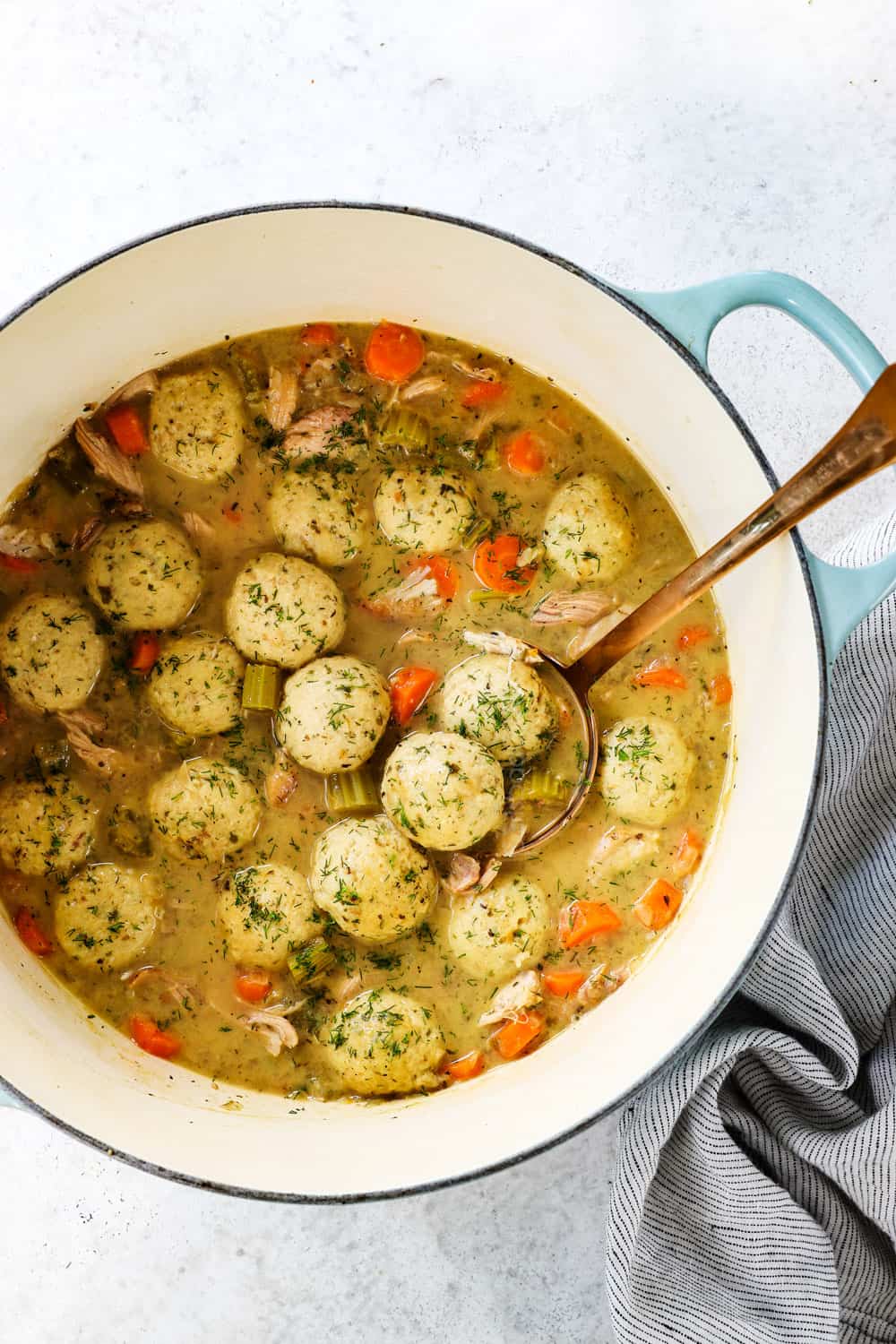 top view of making matzo ball soup in a Dutch oven garnishing with fresh dill