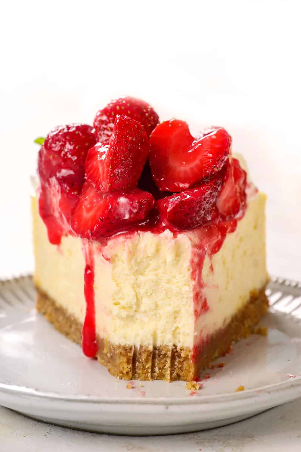 up close of a piece cheesecake with a bite taken out showing how creamy it is