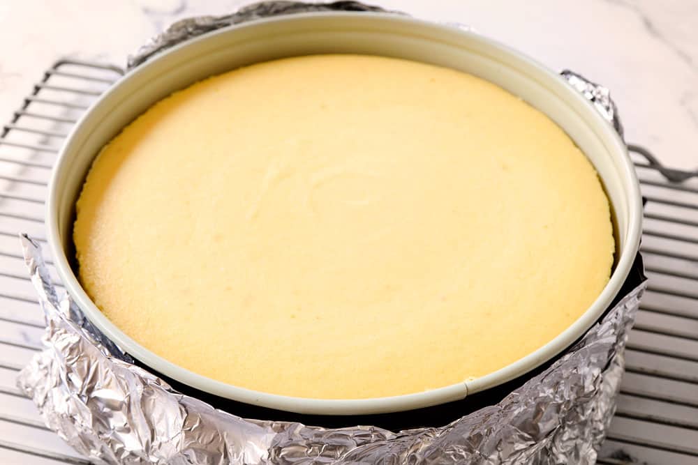 showing how to make strawberry cheesecake by cooling lemon cheesecake on a wire rack