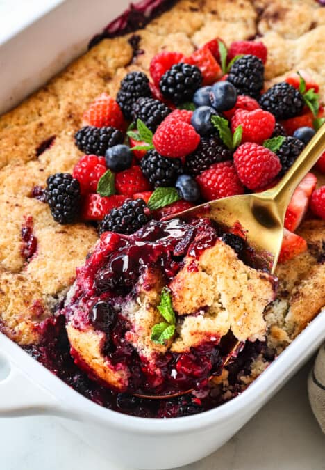 scooping up the mixed berry cobbler showing the juicy berries and golden biscuit topping