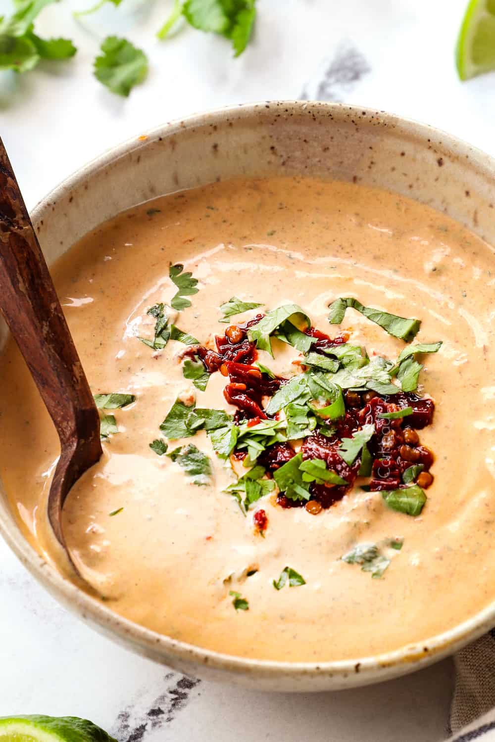 showing how creamy chipotle southwest sauce is by dipping a spoon in a bowl of the sauce