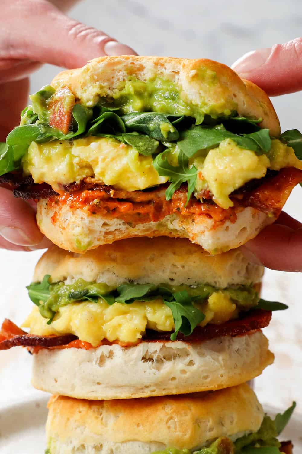 picking up a breakfast sandwich with cheese and eggs on muffins