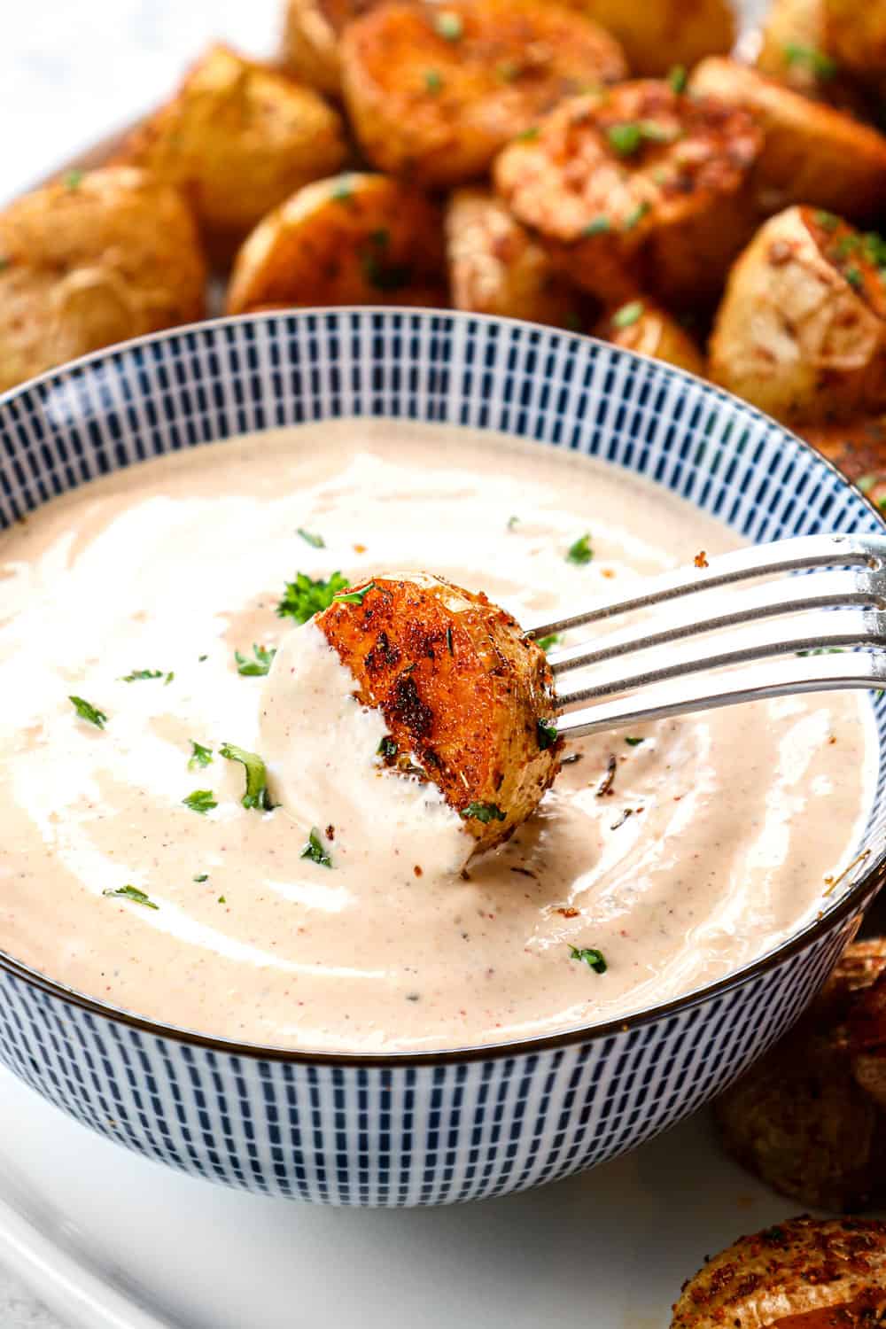 up close dipping Cajun potatoes roasted in the oven with remoulade