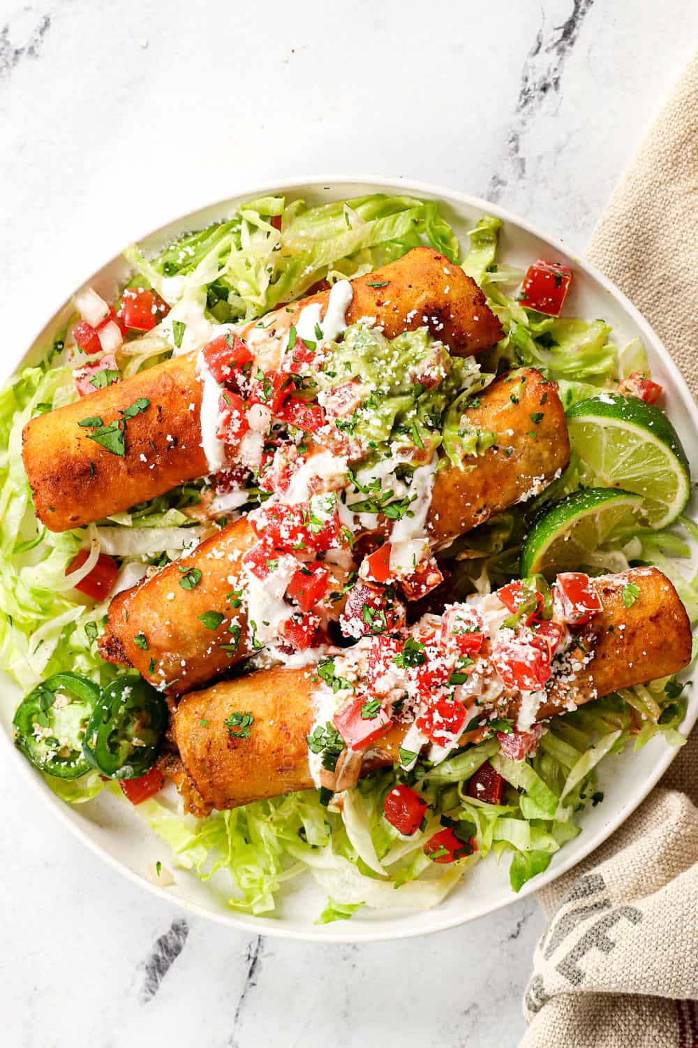 serving taquito recipe with shredded lettuce, sour cream and guacamole