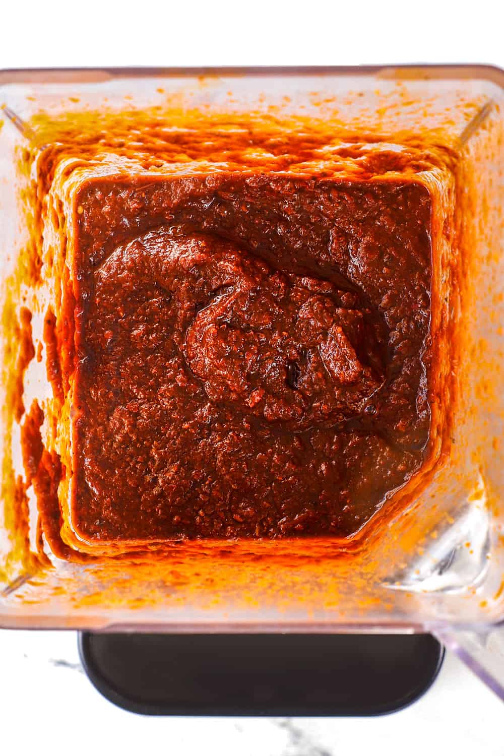 showing how to make adobo sauce by blending softened chilies, tomatoes, garlic and onions in a blender