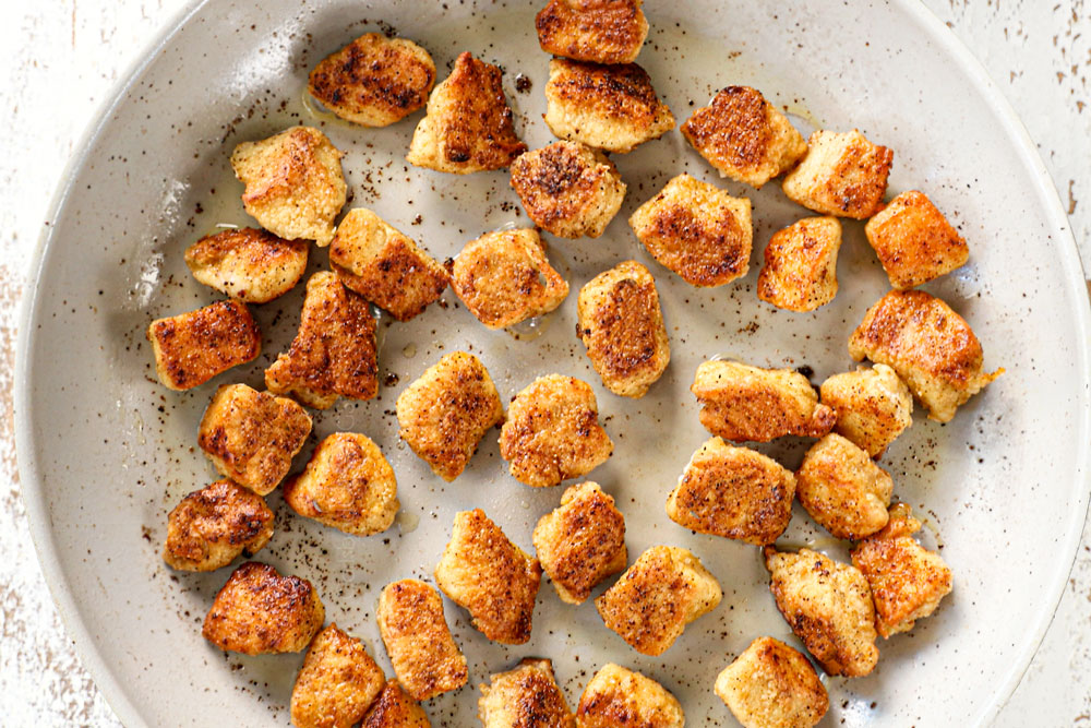 showing how to make black pepper chicken by cooking chicken in a skillet