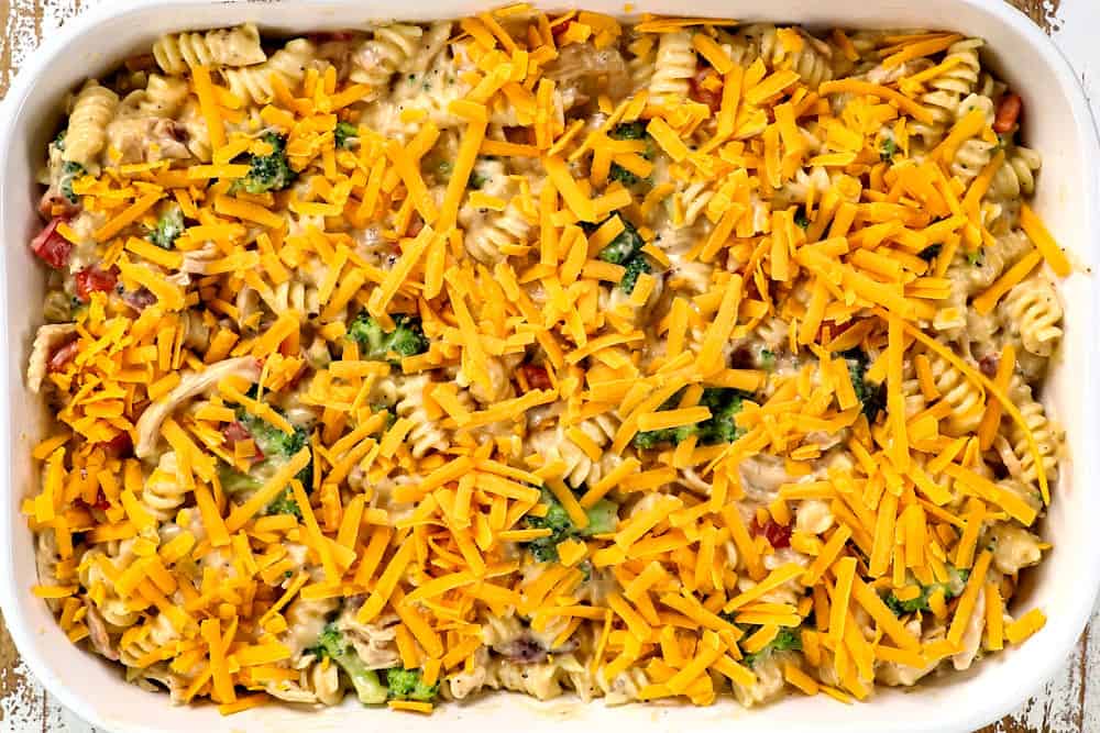 showing how to make bacon chicken ranch casserole by adding cheddar cheese to top of 9x13 baking dish