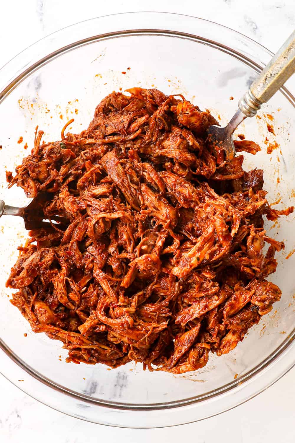 showing how to make chicken birria tacos recipe by shredding the chicken adobado