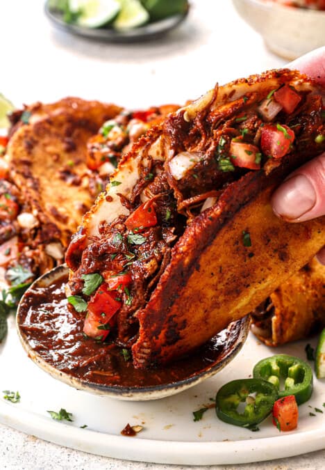 showing how to serve chicken birria tacos by dipping into consume