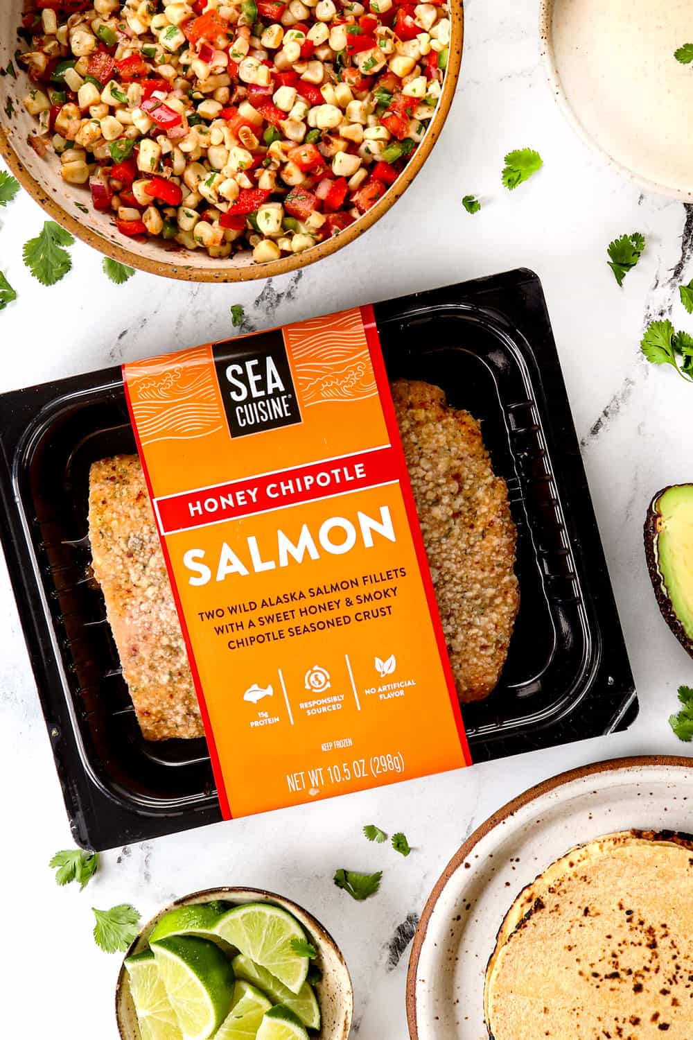 top view of ingredients to make easy fish tacos with salmon, corn salsa, limes and avocados