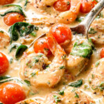 up close of scooping up creamy Tuscan shrimp with garlic