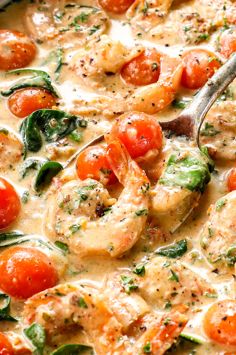 up close of scooping up creamy Tuscan shrimp with garlic