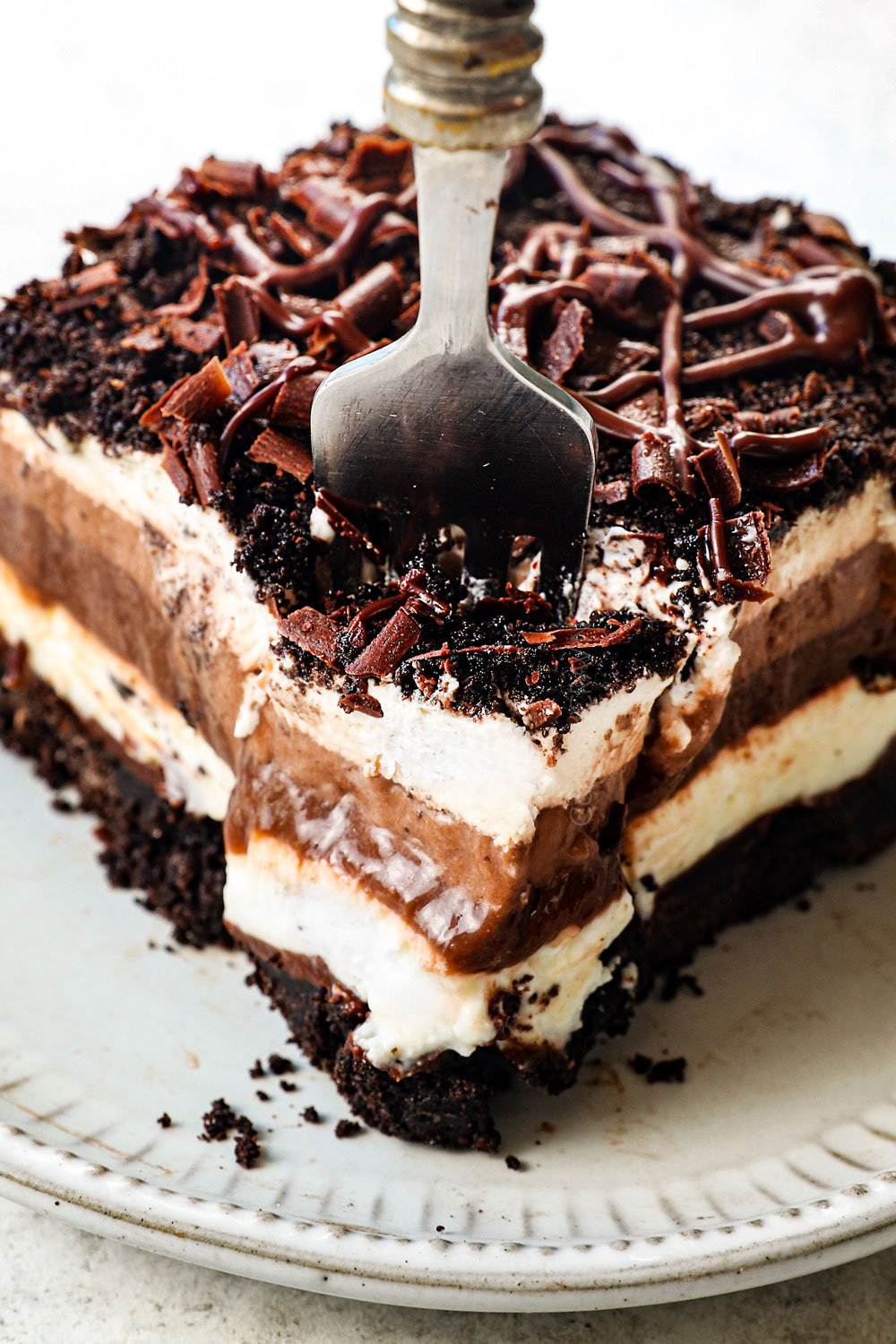 a fork taking a bite of of a slice of chocolate lasagna with Oreos and chocolate pudding
