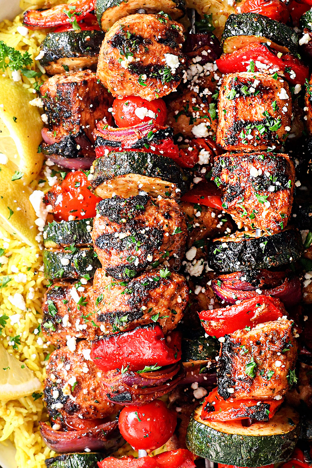 up close of Greek Chicken Kabobs with rice garnished with feta showing how juicy the chicken is