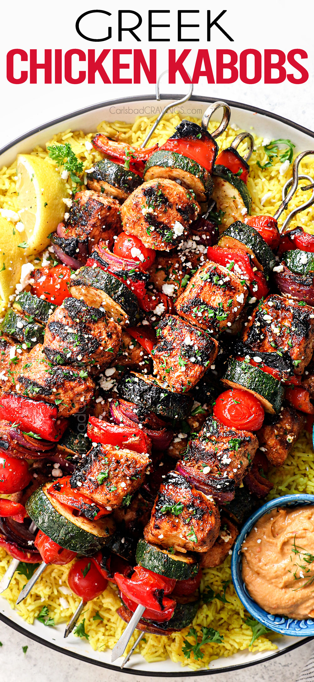 top view of Greek chicken kabobs on a plate with rice, tzatziki and hummus showing how to serve the kabobs