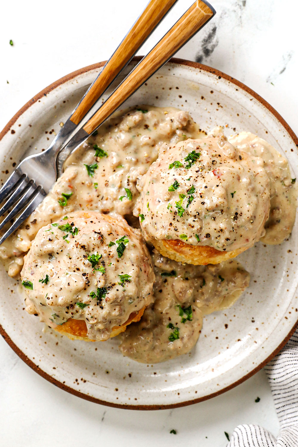 top view of a plate of sausage gravy and biscuits garnished by parsley
