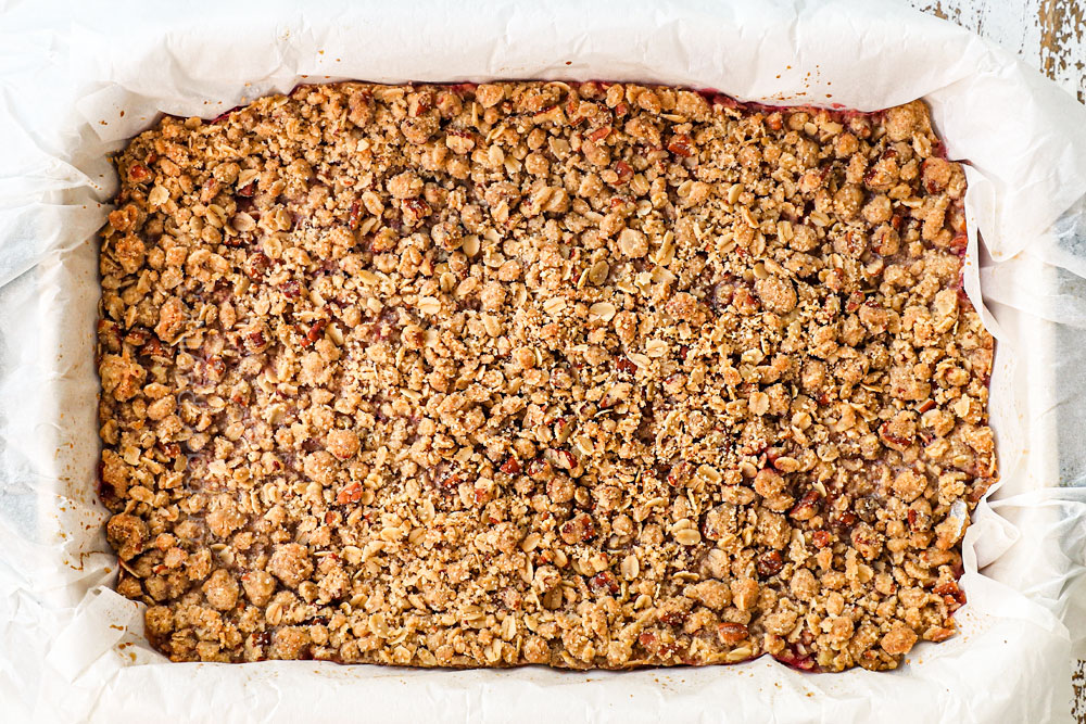 showing how to raspberry bars by baking until the oatmeal crumble topping is golden and crispy