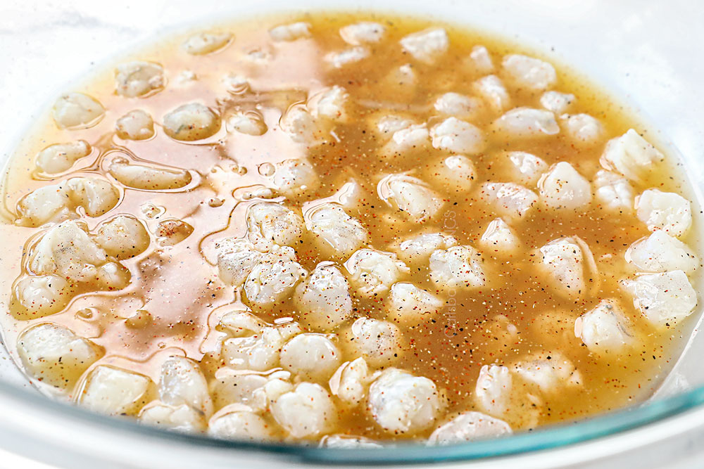 showing how to make shrimp ceviche recipe (ceviche de camaron) by marinating the shrimp in lime juice in a glass bowl until opaque