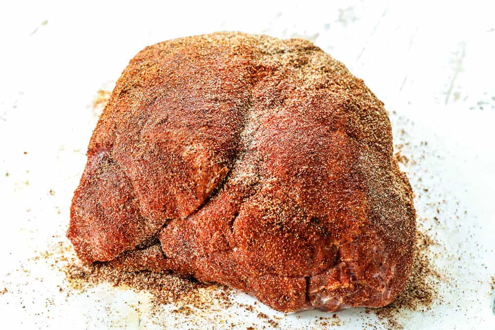 showing how to make BBQ pulled pork by rubbing spices all over the pork