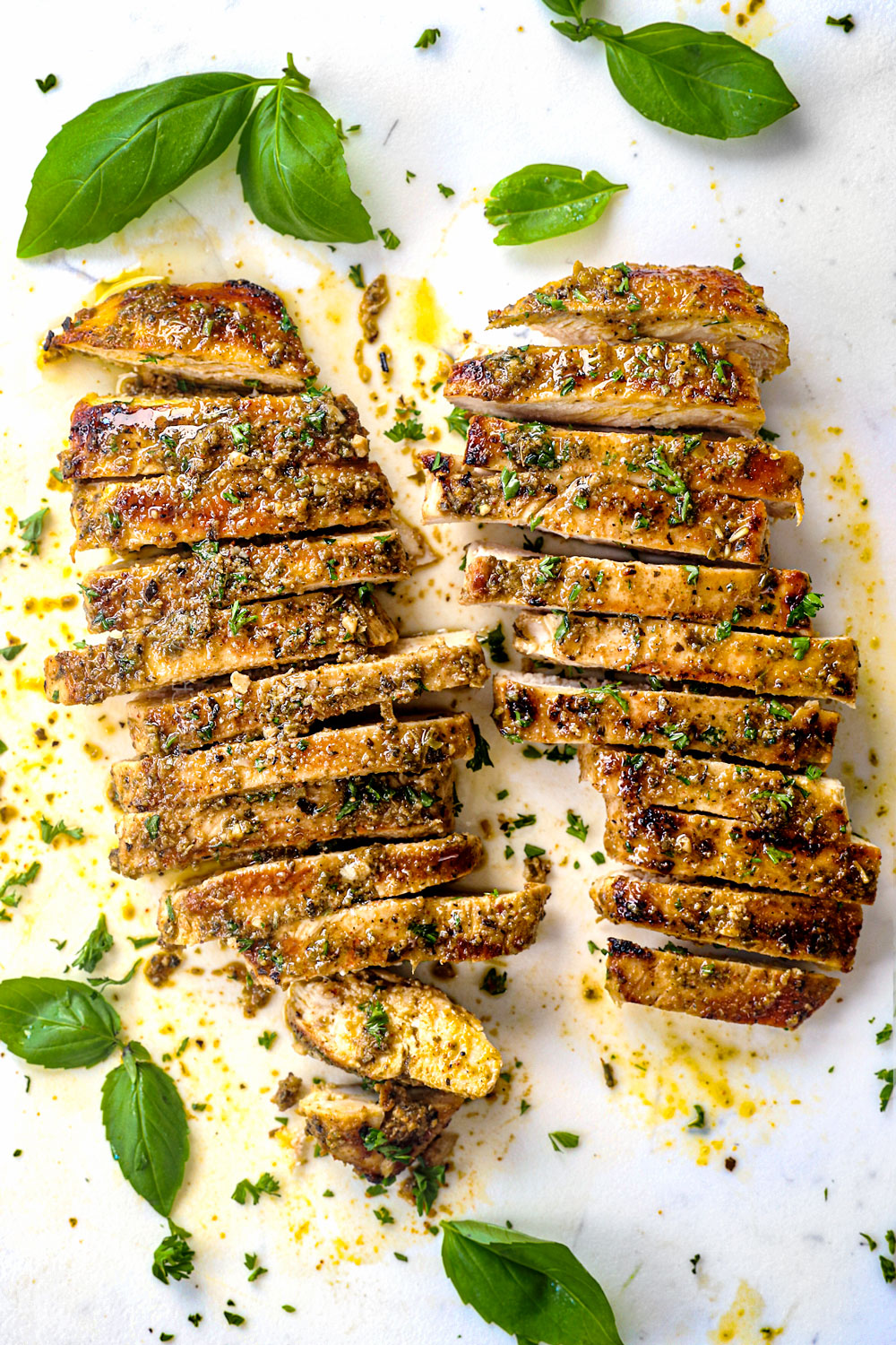 top view of Marinated Italian chicken on a cutting board brushed with pesto