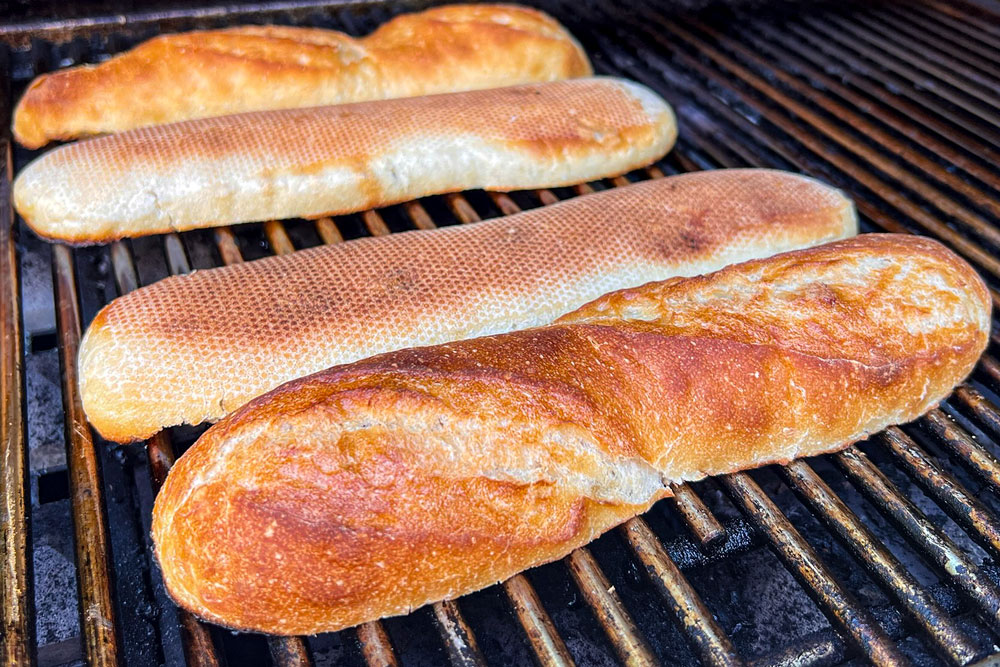 showing how to make banh mi sandwich recipe by toasting he baguettes on the grill before stuffing