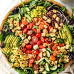 showing how to make garden salad recipe by adding tomatoes, cucumbers, carrots, red onions, avocados, croutons and cheese to a bowl