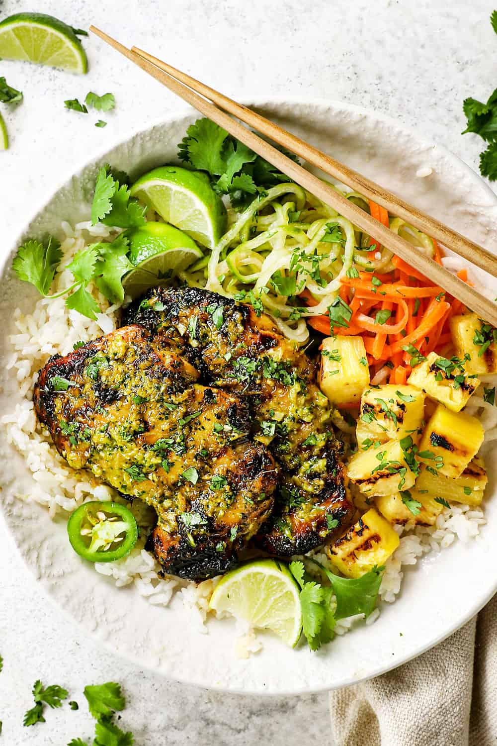 showing how to serve thai chicken recipe by adding chicken to a bowl with rice and pickled vegetables