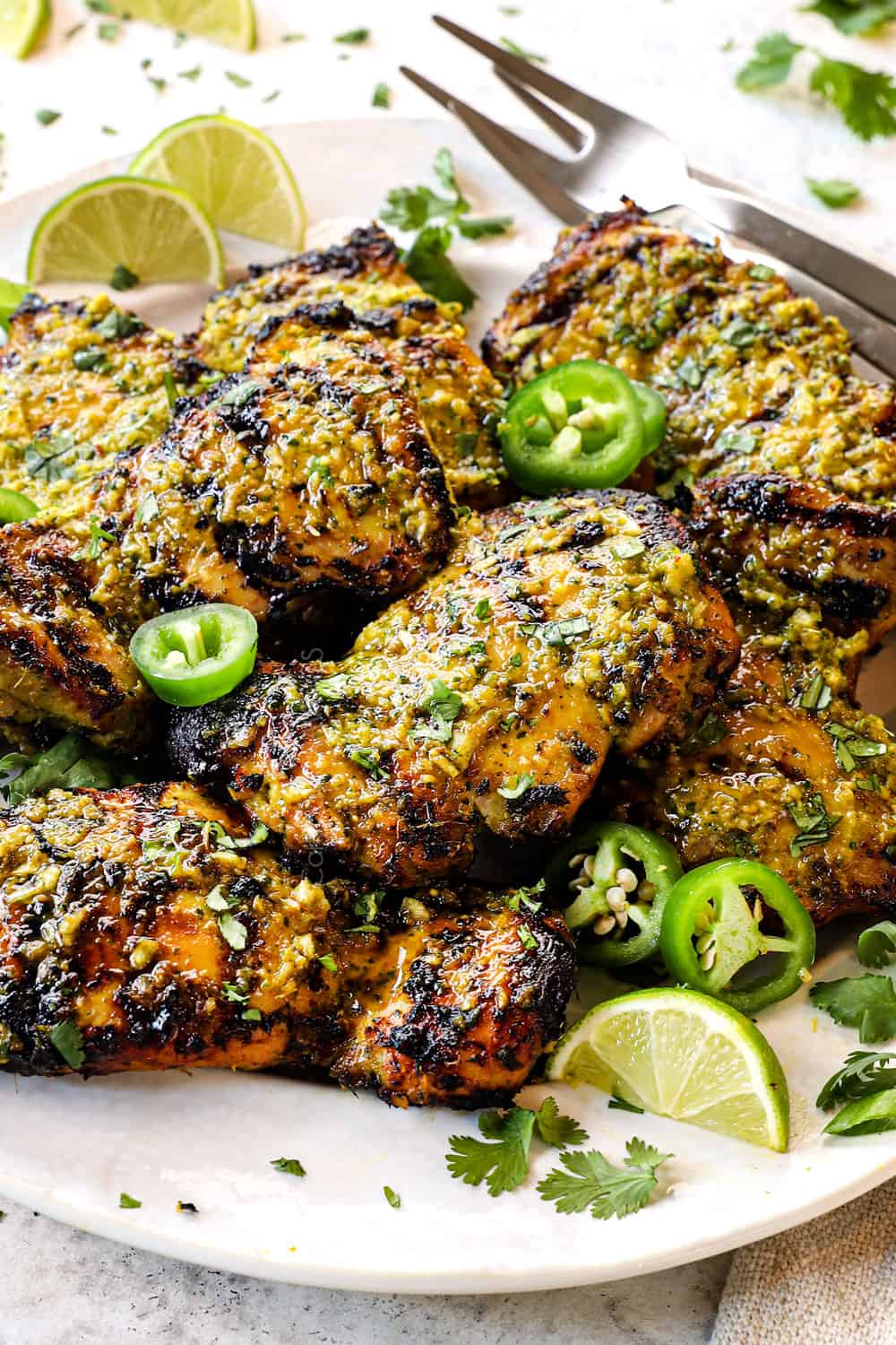 side view of Thai Chicken on a plate serving with slices of lime, jalapenos and fresh cilantro