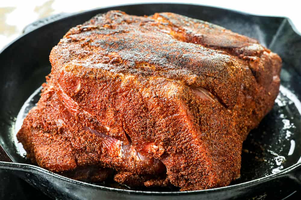 showing how to make pulled pork sandwiches by searing pork butt in a cast iron skillet