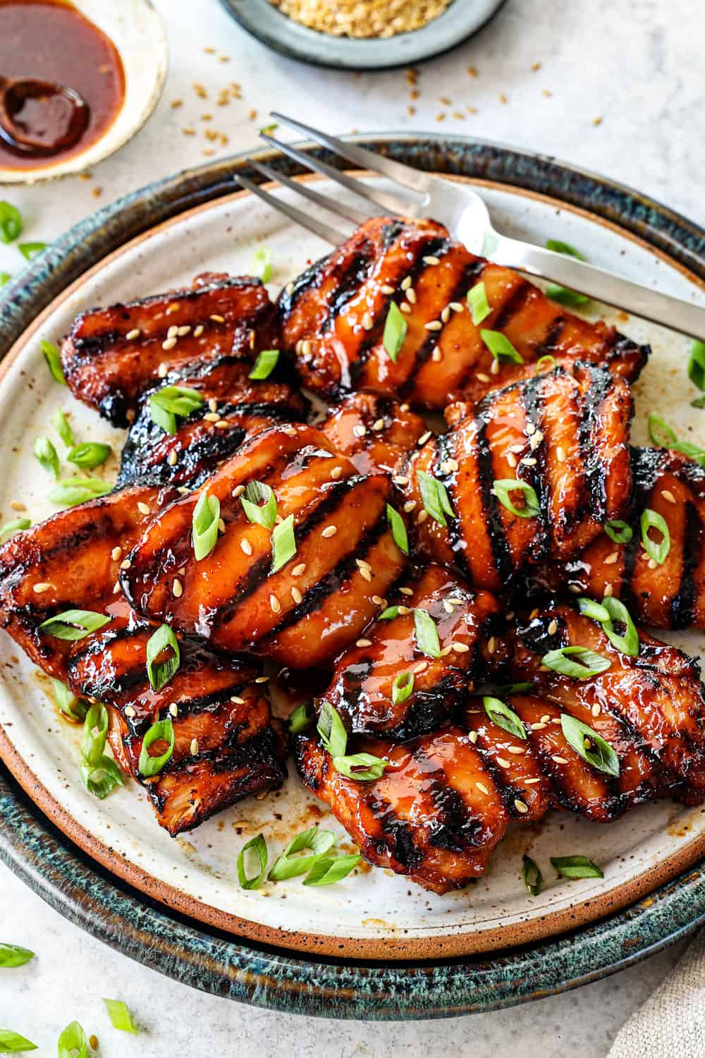 serving boneless grilled chicken thighs on a plate garnished by green onions