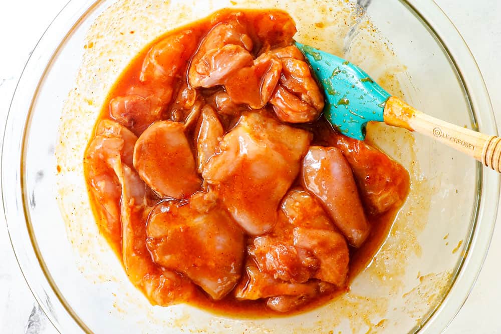 showing how to to make grilled chicken thighs recipe by marinating the chicken in a glass bowl