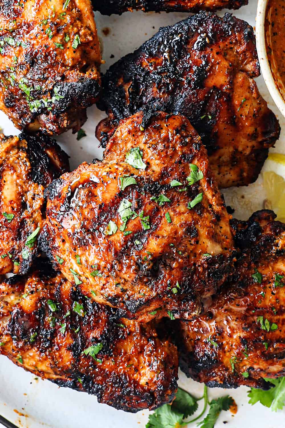 up close of peri peri chicken (piri piri chicken) on a serving platter garnished by cilantro