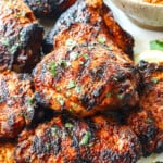 peri peri chicken recipe (piri piri chicken) stacked on a serving platter with a side of peri peri sauce
