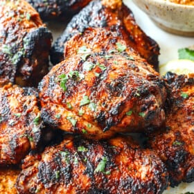peri peri chicken recipe (piri piri chicken) stacked on a serving platter with a side of peri peri sauce