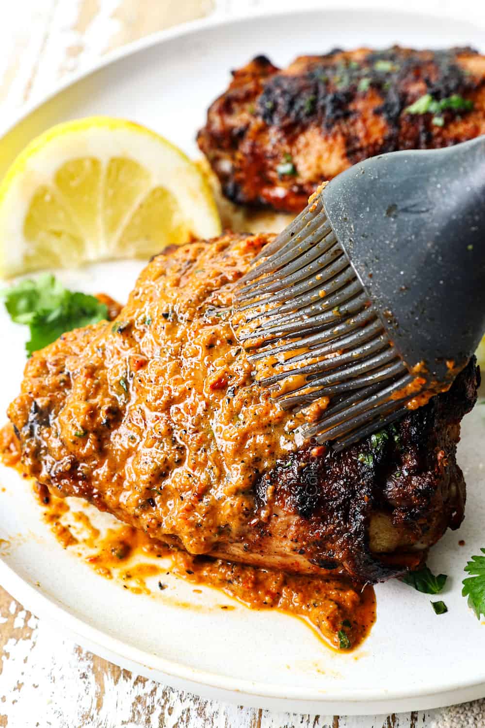 brushing grilled peri peri chicken (piri piri chicken) with peri peri sauce after it's cooked