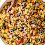 top view of taco pasta salad recipe in a white bowl with pasta, ground beef, cheese, lettuce, black beans, corn, avocados, olives, jalapenos and cilantro