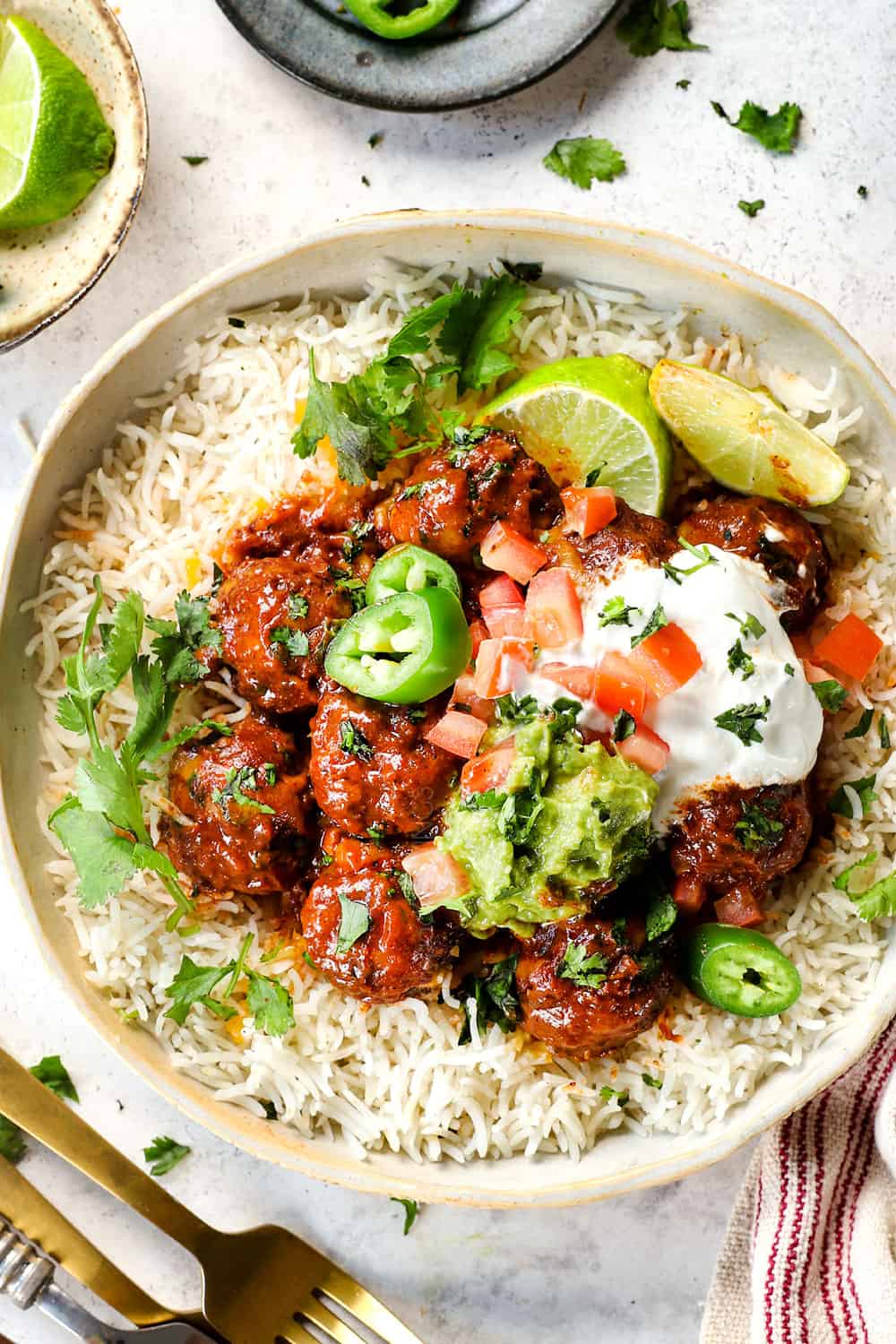 top view of serving baked enchilada meatballs over rice with guacamole, sour cream and cilantro