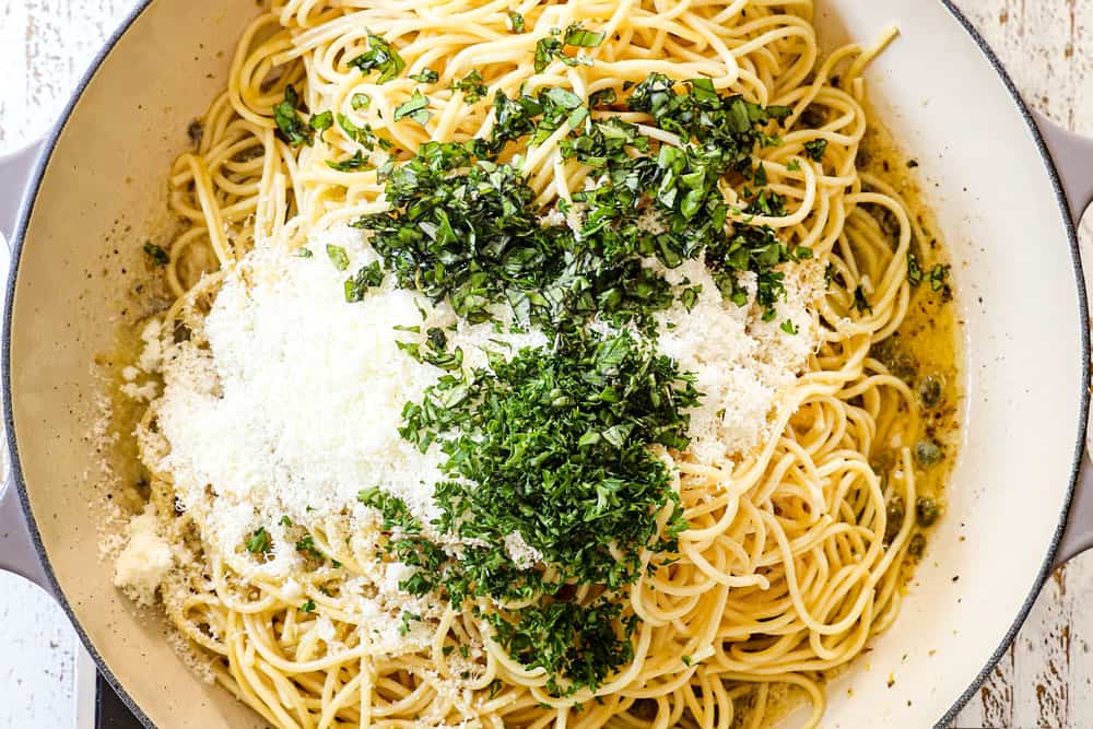 showing how to make lemon pasta (pasta al limone) by adding Parmesan, basil and parsley to the pasta