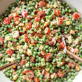 showing how to make pea salad recipe by tossing peas, bacon, cheese, onions, and creamy dressing together in a bowl