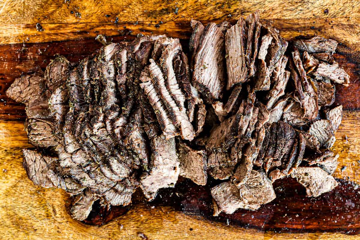 showing how to make Crockpot Philly Cheesesteak by thinly slicing the steak across the grain