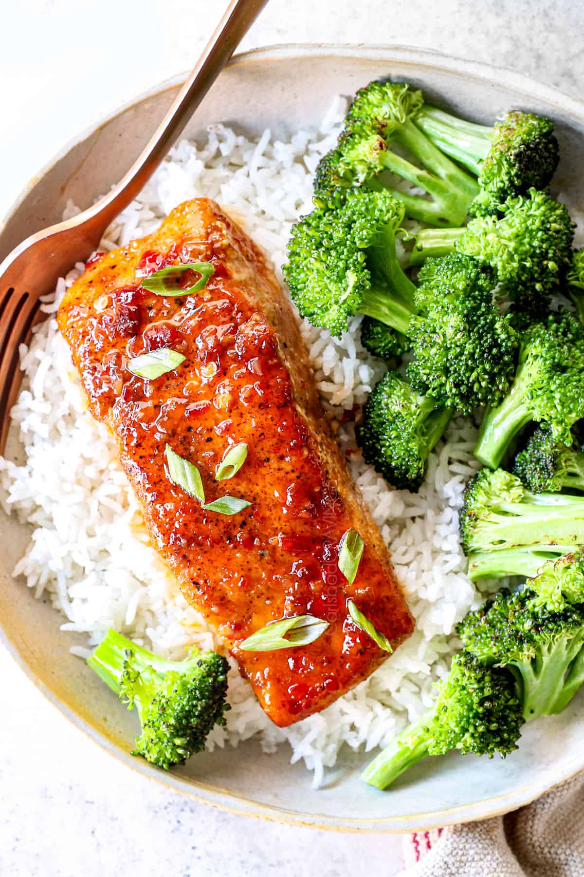 showing how to serve Firecracker salmon by serving over rice garnished with green onions