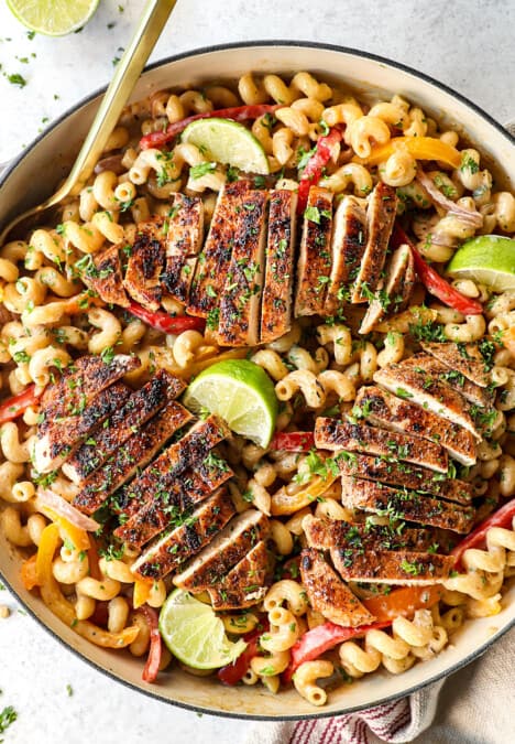 showing how to make jerk chicken pasta (Rasta pasta) by adding chicken to top of pasta with bell peppers