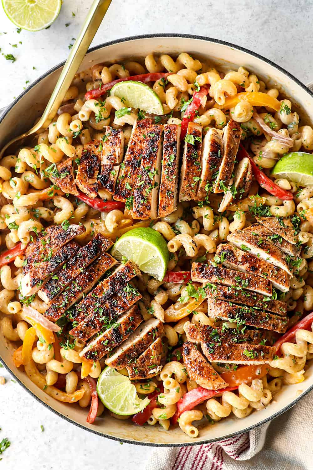 showing how to make jerk chicken pasta (Rasta pasta) by adding chicken to top of pasta with bell peppers