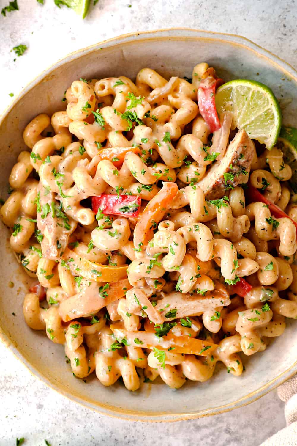 top view of serving jerk chicken pasta (Rasta pasta) in a bowl garnished with parsley and lime
